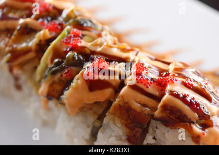 Primo piano artistico di sushi drago rosso rotolo con salmone e caviale Foto Stock