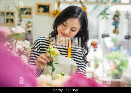 Piuttosto giovane fioraio con bouquet in negozio di fiori Foto Stock