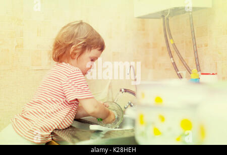 Baby ragazza lava stoviglie in cucina Foto Stock