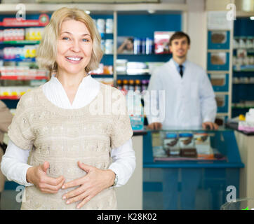 Donna matura vicino al contatore in farmacia farmacia Foto Stock