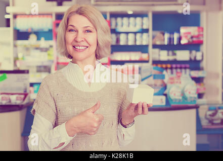 Gioioso sorridente donna matura l'acquisto di medicine in farmacia Foto Stock