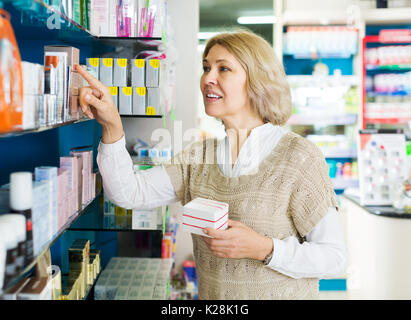 Anziani femmina bionda vicino al contatore in farmacia farmacia Foto Stock