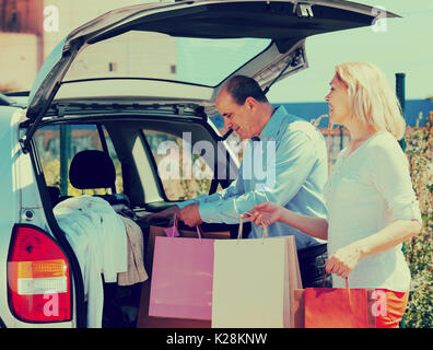 Senior sorridente coppia matura dopo lo shopping gli acquisti di imballaggio Foto Stock