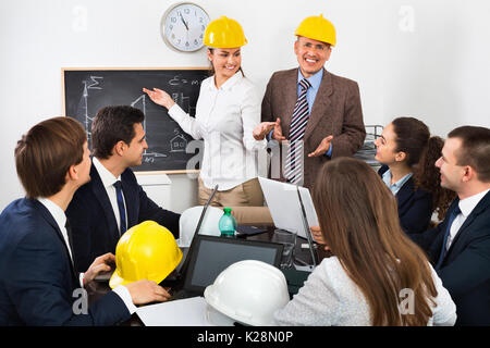 Professionisti del settore energetico con i laptop e caschi con riunione di lavoro Foto Stock