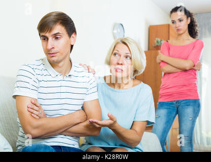 Senior madre-in-legge cercando di conciliare la coppia giovane in ambienti interni Foto Stock