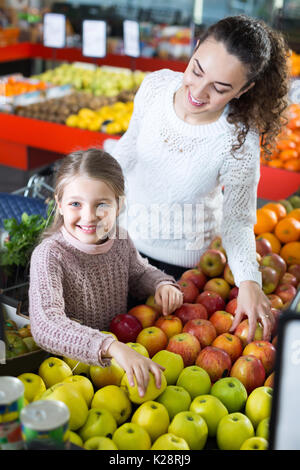 Ritratto di sorridenti giovane donna e bambina acquisto di mele mature al mercato Foto Stock