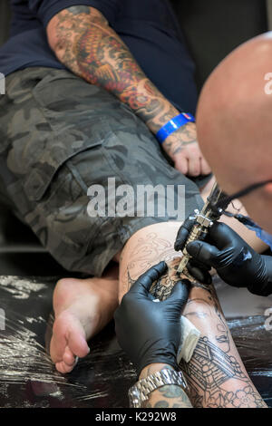 Cornovaglia Tattoo Convention - una vista ingrandita di tattooist Andy Middleton tatuaggio la gamba di un cliente al Cornwall Tattoo Convention. Foto Stock