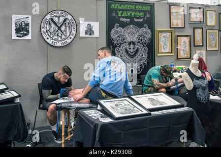 Tatuaggio - un uomo avente la sua gamba tatuati in Cornovaglia Tattoo Convention. Foto Stock