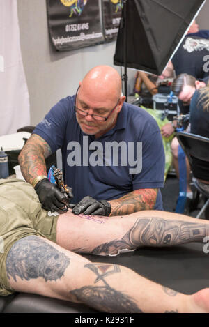 Cornovaglia tattoo convention - un uomo avente la sua coscia tatuati in Cornovaglia tattoo convention. Foto Stock
