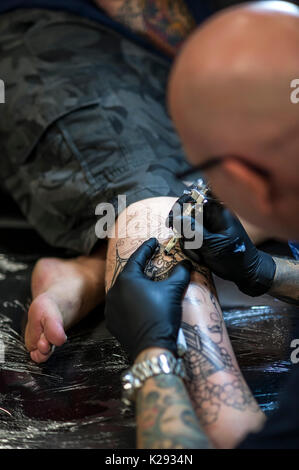 Cornovaglia Tattoo Convention - una vista ingrandita oftTattooist Andy Middleton tatuaggio la gamba di un cliente al Cornwall Tattoo Convention. Foto Stock