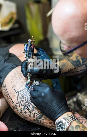 Tatuaggio - un primo piano della progettazione essendo tatuato sulla gamba di un cliente al Cornwall Tattoo Convention. Foto Stock