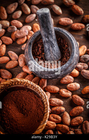 Primo piano della terra le fave di cacao in mortaio di pietra Foto Stock