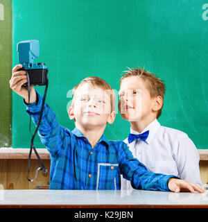 Due compagni di scuola fare selfie a lavagna nella scuola. torna al concetto di scuola di sfondo Foto Stock