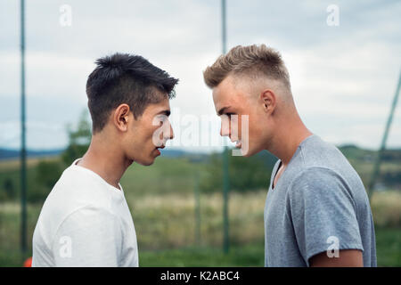 Due ragazzi sul parco giochi guardando ogni altro con odio. Foto Stock