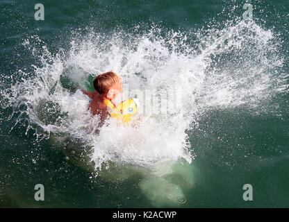 Un uomo sbarca in mare su un gommone dopo il salto della parete del mare durante il tempo caldo in Broadstairs Kent. Foto Stock