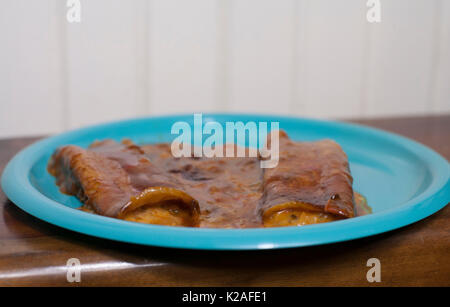 Chiudere fino a tre formaggi enchiladas su un bel piatto di colore blu Foto Stock