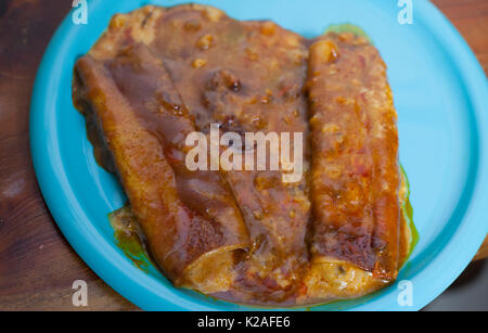 Chiudere fino a tre formaggi enchiladas su un bel piatto di colore blu Foto Stock