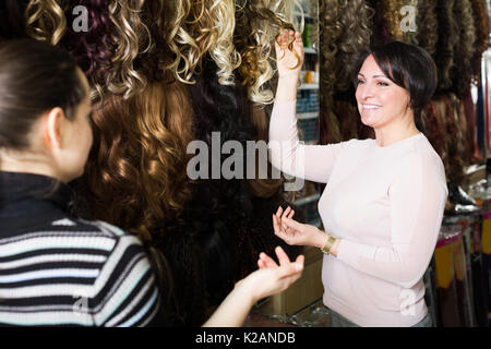 Due femmina sorridente i clienti che acquistano un allungamento dei capelli in salone Foto Stock