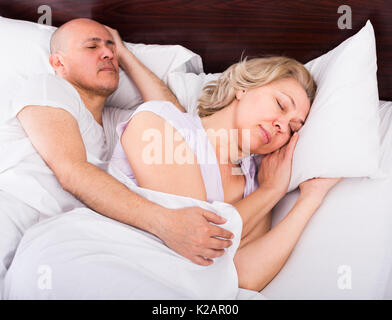 Amorevole famiglia maturi accoppiare a tenuta di dormire nel letto a notte. Focus sulla donna Foto Stock