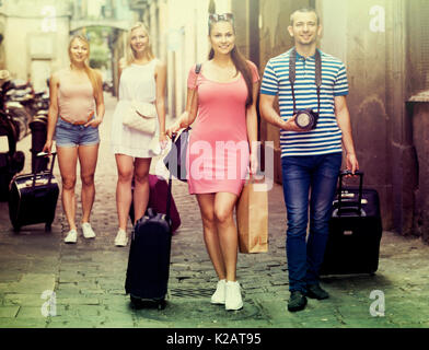Ritratto di felice coppia turisti tenendo a piedi e trascinando valigie in città nel giorno di agosto Foto Stock