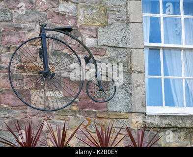 Vecchio modello di bicicletta penny Farthing presentato sulla parete di pietra di un vecchio muro di pub, Candlemaker Row, Edimburgo, Scozia, Regno Unito Foto Stock