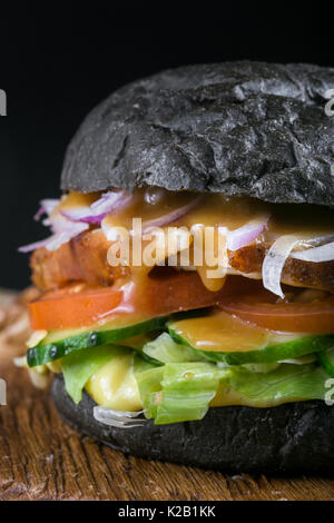 Freschi e saporiti burger su sfondo nero. In casa bistecca di carne di maiale hamburger cipolla, pomodoro, lattuga e formaggio con ingredienti Foto Stock