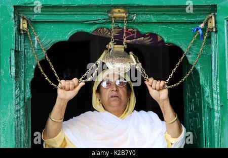 India. Il 29 agosto, 2017. Una donna del Kashmir detiene una icona religiosa catena e offre preghiere all'entrata del santuario di Shah e Hamdan sulla morte anniversario dello studioso sufi Mir Syed Ali Hamadani a Srinagar, controllata indiano Kashmir, martedì 29 agosto 2017 centinaia di Kashmiris ha visitato il santuario di Hamadani, che è nato in Iran, Kashmir ha visitato diverse volte e ha giocato un ruolo influente nella diffusione dell Islam in valle. Credito: Umer Asif/Pacific Press/Alamy Live News Foto Stock
