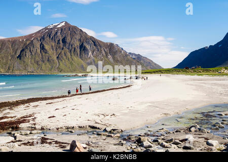I turisti pagaiando sulla tranquilla Skagsanden sabbiosa spiaggia in estate. Flakstad, Flakstadøya isola, isole Lofoten, Nordland, Norvegia e Scandinavia Foto Stock