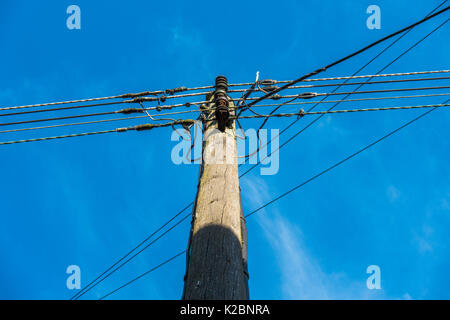 Un ambiente familiare e tradizionale, soleggiato palo del telegrafo e cavi telefonici, visto dal di sotto, contro un cielo blu chiaro. Langtoft, Lincolnshire, Inghilterra, Regno Unito. Foto Stock