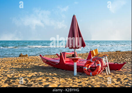 Lifeguard Tools, ombrello,salvagente e la barca di salvataggio contro la spiaggia, il mare e il cielo Foto Stock