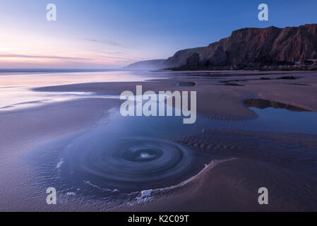 Una lunga esposizione di Sandymouth Bay, al crepuscolo mostra eddies in acqua, Bude, Cornwall, Regno Unito. Aprile 2015. Foto Stock