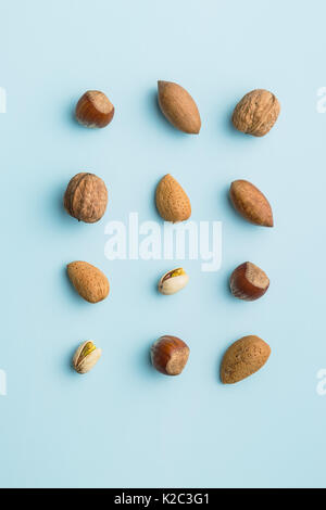 Diversi tipi di dadi in breve su sfondo blu. Frutta secca. Foto Stock