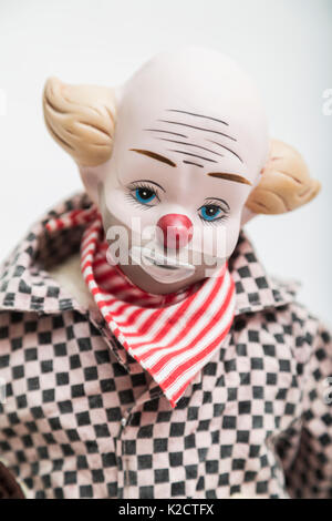 Ceramica Porcellana fatti a mano bambola vintage del clown triste con gli occhi blu, naso rosso, capelli biondi, metà bold in plaid bianco e nero shirt, rosso bandana band Foto Stock