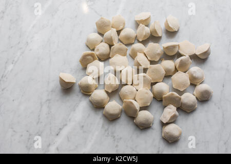 Materie congelati gnocchi di pasta close up su bianco rustico in pietra sullo sfondo Foto Stock