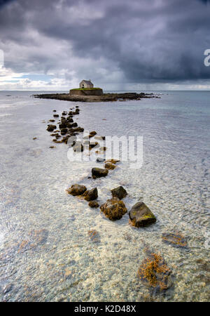 Nuvole scure su St Cwyfan la Chiesa, su una piccola isola nel Porth Cwyfan, vicino Aberffraw, Isola di Anglesey, Galles, aprile 2014. Foto Stock