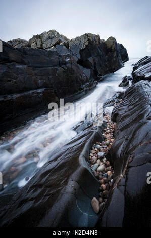 Una lunga esposizione di acqua correre attraverso l'ingresso a, Saligo Bay, Islay, Ebridi Interne, febbraio. Foto Stock