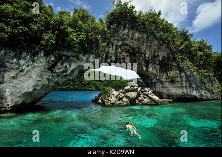 Snorkeler di fronte all'arco tra le isole rocciose, Koror, Palau, Mare delle Filippine Foto Stock