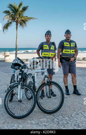Uomini e donne poliziotti militari brasiliani in piedi con le loro biciclette alla spiaggia Praia Grande, Stato di San Paolo, Brasile. Foto Stock
