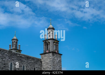 Galway, Irlanda - 5 Agosto 2017: due in pietra grigia torri sottili con piccole cupole e croce al fianco della entrata principale presso la navata centrale del Duomo. Pictu Foto Stock