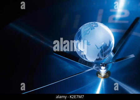 Concetto di tempo. closeup del globo di vetro giacente sul metallo blu orologio Foto Stock