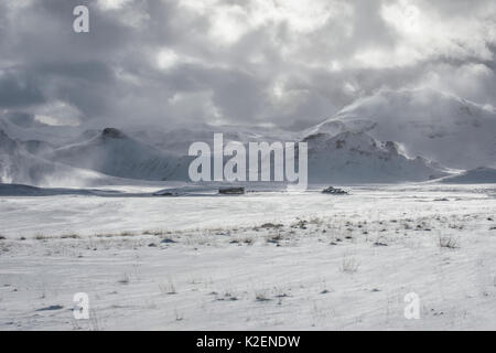 Podere isolato nel paesaggio innevato con le montagne al di là. Grundarfjordur, Snaefellsnes Peninsula, Islanda, marzo 2014. Foto Stock