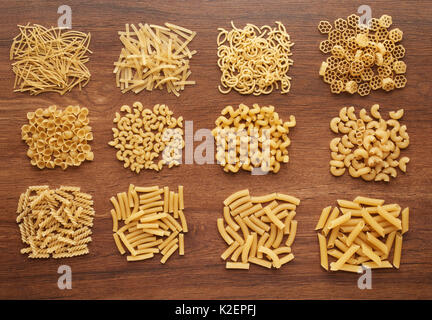 Chiudere fino a diversi tipi di pasta secca su legno scuro tabella, vista dall'alto Foto Stock