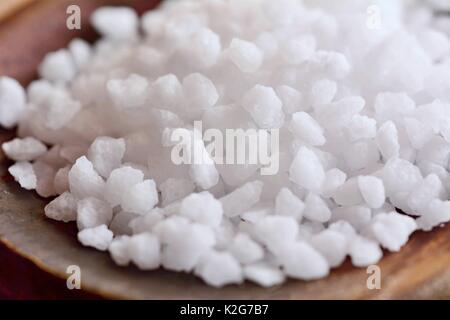 Ripresa macro di un bianco chiaro dei cristalli di sale su un cucchiaio di legno. Foto Stock