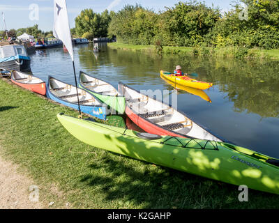 Un canoeist passa da colorati canoe ormeggiato sul Grand Union Canal a Marsworth, nella valle di Aylesbury, Bucks Foto Stock