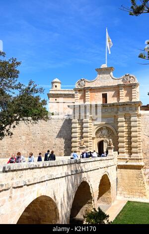 Turisti attraversando il ponte pedonale che conduce alla porta della città e il centro città, Mdina, Malta, l'Europa. Foto Stock