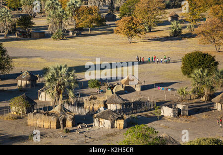 Villaggio nativo appena al di fuori della zona protetta, prominente di un gruppo di giovani uomini pronti per una partita di calcio, vista aerea, Okavango Delta, Botswana Foto Stock