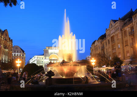 Le fontane colorate sulla piazza della Vittoria, con l'Opera House dietro, al tramonto, sulla piazza della Vittoria, in Timisoara, nell ovest della Romania Foto Stock