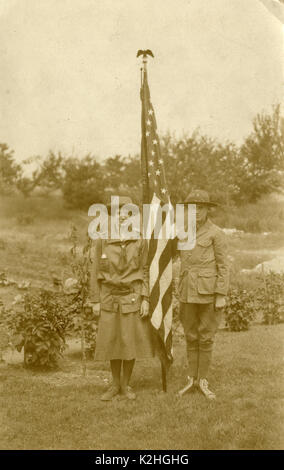 Antique c1930 fotografia, ragazza Scout e Boy Scout con bandiera americana. Il ragazzo indossa Converse sneakers. Fonte: fotografia originale. Foto Stock