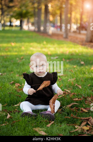 Ragazza carina si siede nel parco in autunno il giorno Foto Stock