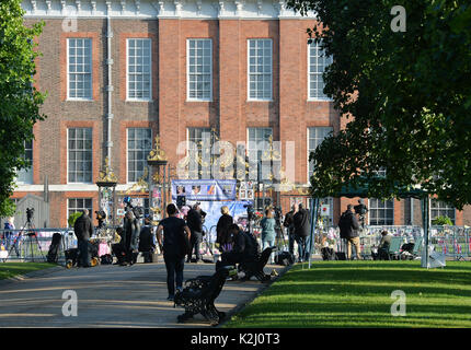 Media raccogliere fuori Kensington Palace a Londra come fiori e omaggi in occasione del ventesimo anniversario della morte di Lady Diana, principessa di Galles, sono a sinistra. Foto Stock